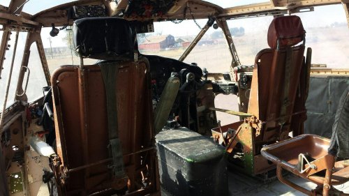 Cockpit of an old aircraft with two pilot seats, control panel, and worn interior details.