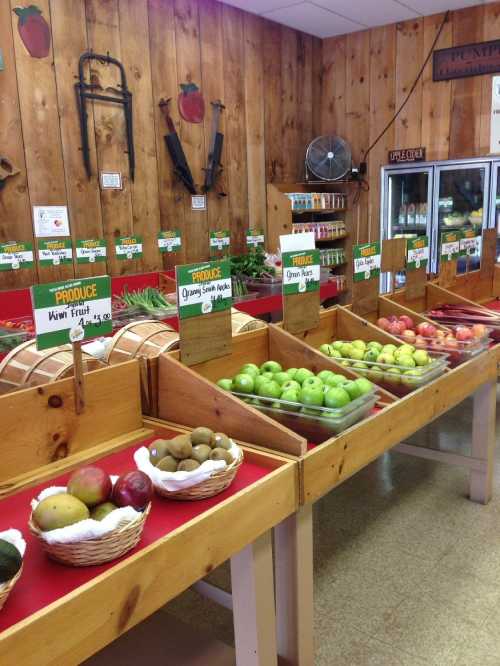 A colorful produce display with various fruits in baskets and wooden crates against a rustic wooden wall.