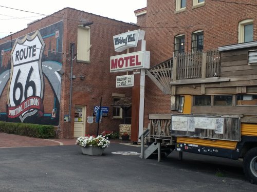 A brick building with a "Motel" sign and a Route 66 mural, featuring a vintage truck parked nearby.