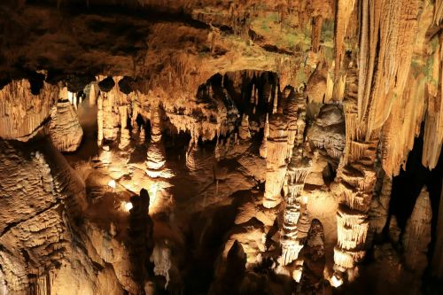 A stunning underground cave with illuminated stalactites and stalagmites, showcasing intricate rock formations.