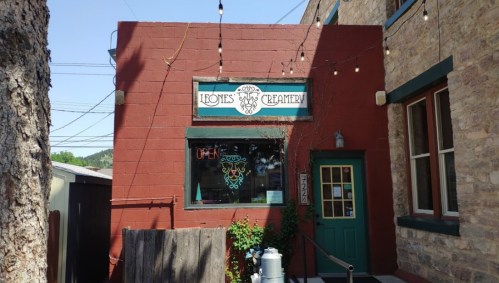 A red building with a sign reading "Leone's Creamery" and an open sign in the window, surrounded by string lights.