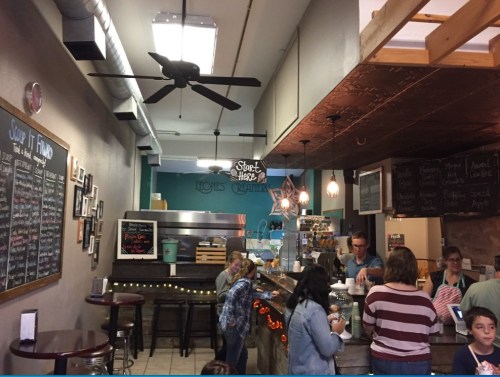 A cozy café interior with a counter, menu boards, and customers enjoying drinks and snacks. Warm lighting and decor.