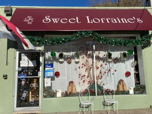 A storefront with a sign reading "Sweet Lorraine's," decorated for the holidays with garlands and festive ornaments.