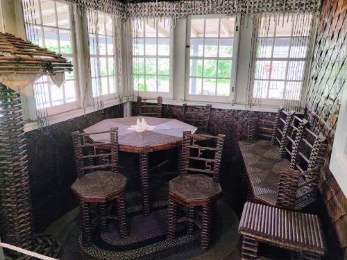 A cozy dining area featuring unique furniture made of woven materials, with large windows letting in natural light.