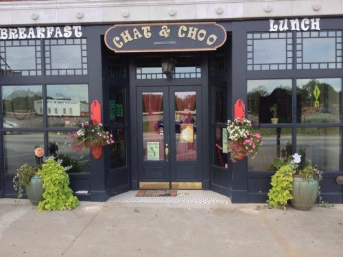 Exterior of a restaurant named "Chat & Choo," featuring a welcoming entrance with flower pots and a sign for breakfast and lunch.