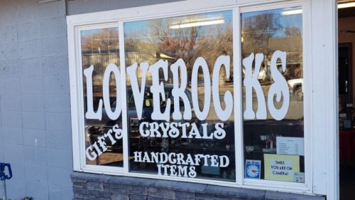 Storefront window displaying "Loverocks" with signs for gifts, crystals, and handcrafted items.