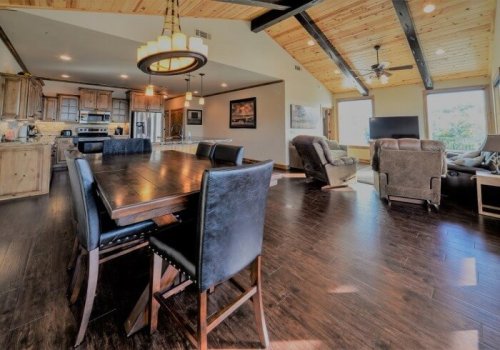 A spacious dining area with a wooden table, black chairs, and a cozy living room in a modern home.