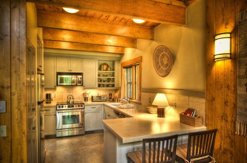 Cozy kitchen with wooden beams, modern appliances, and a warm ambiance, featuring a dining area with two chairs.