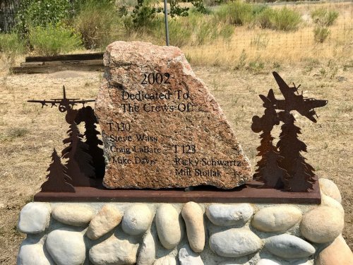 A stone memorial with metal silhouettes of aircraft, honoring the crews of T-130 and T-123, dedicated in 2002.