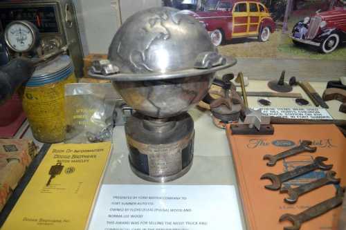 A vintage globe trophy on a display table surrounded by tools, books, and memorabilia.