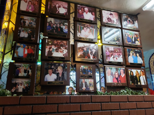A collage of framed photos on a wall, featuring various groups of people at events and gatherings.