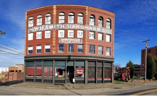 Historic brick building with faded signage for W.H. Smith Hardware Co. Museum, featuring large windows and a clear blue sky.