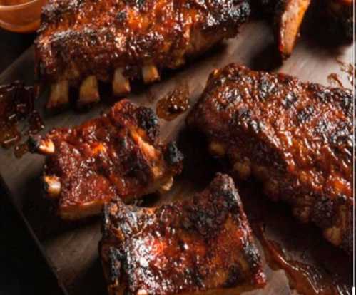 A close-up of glazed, barbecued ribs on a wooden platter, with a rich, caramelized sauce.