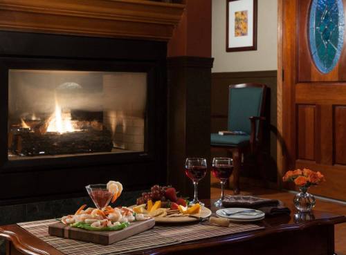 A cozy dining setup with shrimp cocktail, fruit, and wine glasses in front of a warm fireplace.