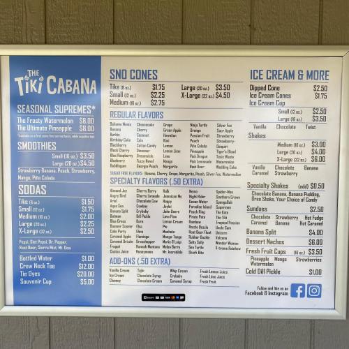Menu board for The Tiki Cabana featuring seasonal supremes, smoothies, sodas, sno cones, and ice cream options.