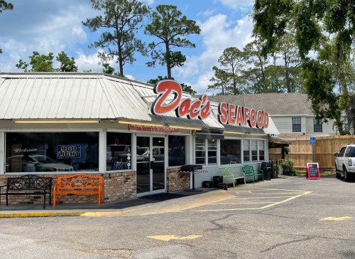 A seafood restaurant named "Doc's Seafood" with outdoor seating and a sunny sky in the background.