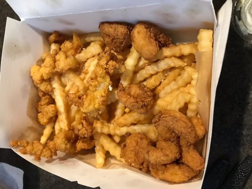 A takeout box filled with crispy fried chicken pieces and crinkle-cut fries.