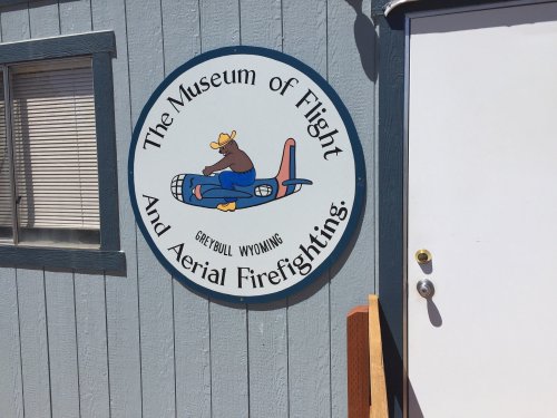 Sign for the Museum of Flight and Aerial Firefighting in Greybull, Wyoming, featuring a cartoon bear on a plane.