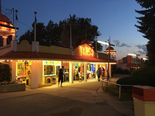 A brightly lit amusement arcade named "Tango" at dusk, with people walking outside and colorful lights glowing.