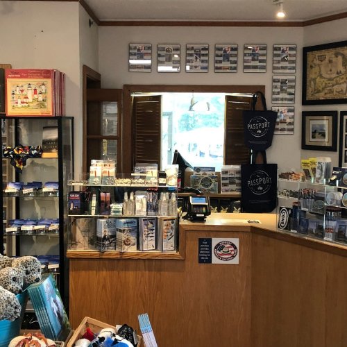 A cozy shop interior with a display counter, brochures, and souvenirs, featuring a window and wall art.