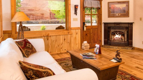 Cozy living room with a white sofa, wooden coffee table, and a fireplace, overlooking a scenic river view.