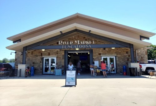 Exterior of River Market in Tuscaloosa, featuring a stone facade and people entering and exiting the building.