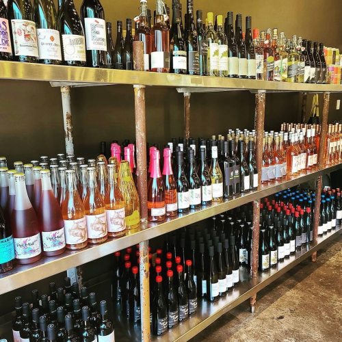 A shelf filled with various bottles of wine and spirits, showcasing a range of colors and labels.
