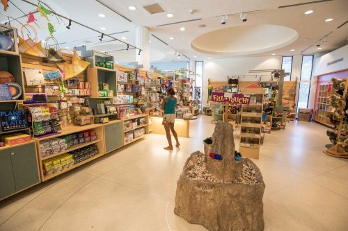 A brightly lit store with shelves of educational toys and games, featuring a central display and a customer browsing.