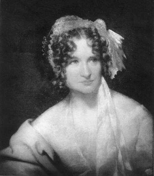 A portrait of a woman with curly hair, wearing a light dress and a ribbon, set against a dark background.