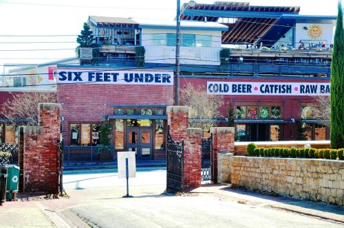 Entrance to "Six Feet Under," a restaurant featuring cold beer, catfish, and a raw bar, with a brick facade and outdoor seating.