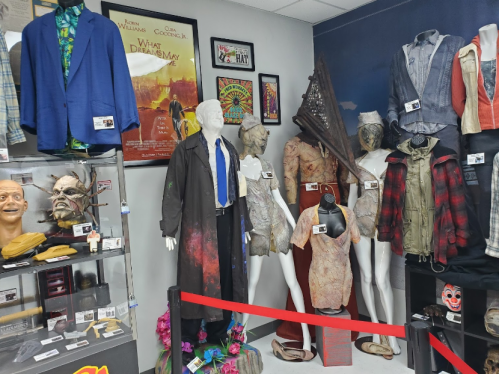 Display of costumes and props, including mannequins in various outfits and a collection of masks and memorabilia.