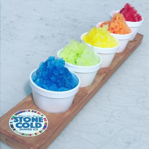 Five colorful cups of shaved ice in blue, green, yellow, orange, and red, displayed on a wooden tray.