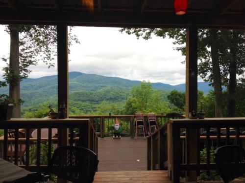 View from a wooden deck overlooking lush green mountains under a cloudy sky.