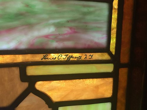 Stained glass detail featuring the signature "Louis C. Tiffany 2.7" on a colorful background.