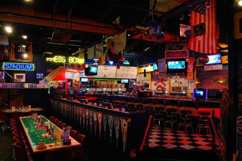 A vibrant sports bar interior with neon signs, checkered flooring, and tables set for dining.