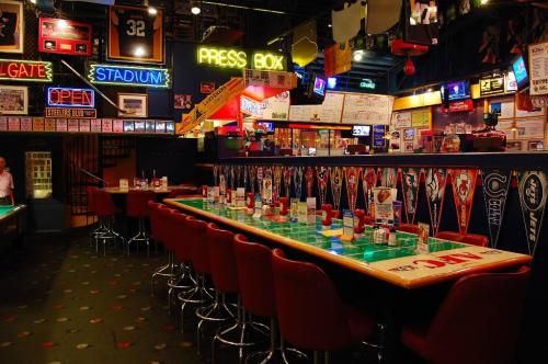 A vibrant sports bar interior with neon signs, banners, and a long bar lined with drinks and seating.