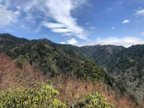 A scenic view of lush green mountains under a blue sky with scattered clouds.