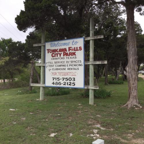 Sign welcoming visitors to Tonkawa Falls City Park in Crawford, Texas, with information on RV spaces and camping.