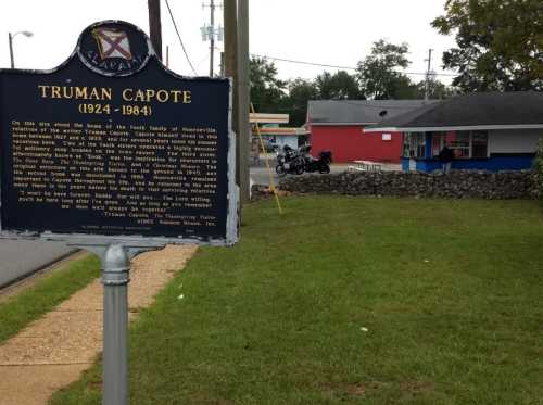 Historical marker for Truman Capote, with a view of a building and motorcycle in the background.