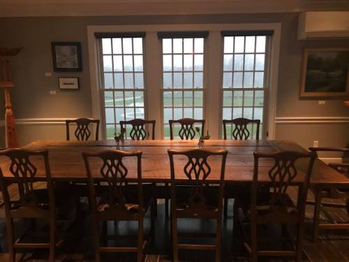 A spacious dining room with a large wooden table and chairs, featuring windows that overlook a foggy outdoor view.