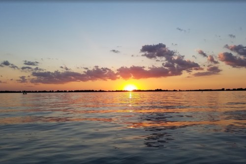 A serene sunset over calm waters, with colorful clouds reflecting on the surface.