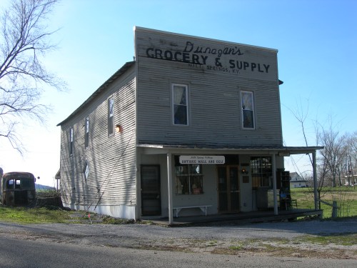 A weathered two-story grocery store with a sign reading "Dungan's Grocery & Supply" in a rural setting.