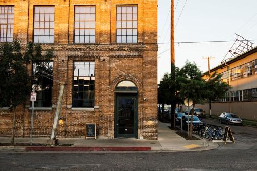 A brick building with large windows, a green door, and trees outside, set in an urban street scene.