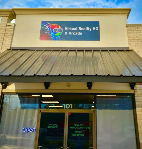 Sign for "Virtual Reality HQ & Arcade" on a storefront, with an open sign visible in the window.