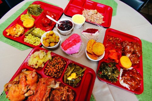 A table set with multiple red trays filled with various dishes, including meats, vegetables, and desserts.