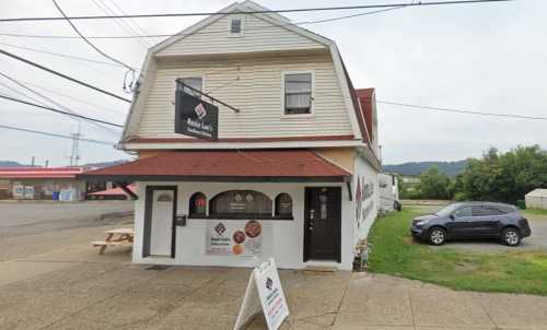 A two-story building with a red roof, featuring a sign for a restaurant and outdoor seating area.