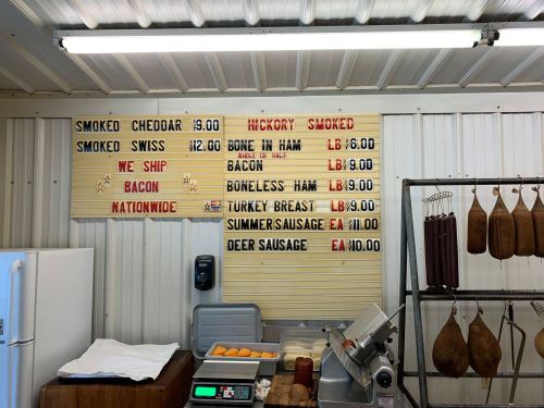 A menu board displaying various smoked meats and prices, including hickory smoked items and shipping options.