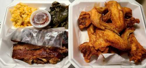 A takeout container with fried chicken wings, ribs, collard greens, and macaroni and cheese.