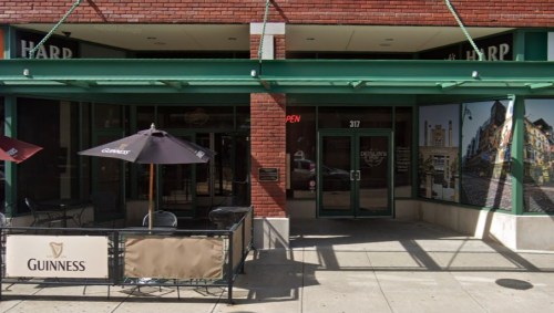 Exterior view of a pub with a Guinness sign, outdoor seating, and a "Open" sign on the door.