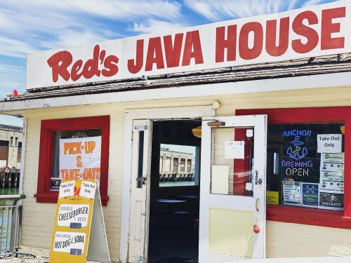 Exterior of Red's Java House with a sign for pick-up and take-out, featuring a menu of burgers and drinks.